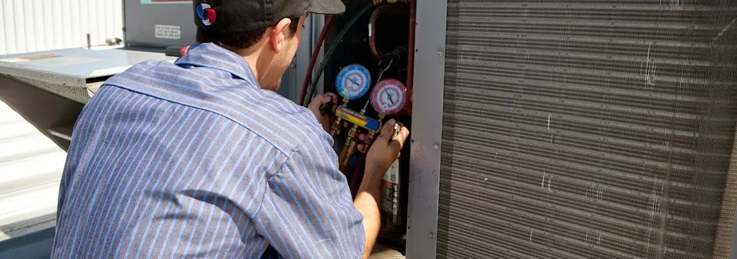 HVAC technician servicing a condenser unit in Hugo