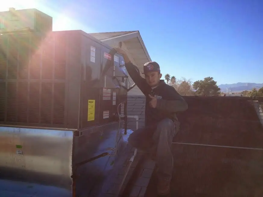 HVAC technician performing Air Duct Cleaning on a rooftop unit in Hugo